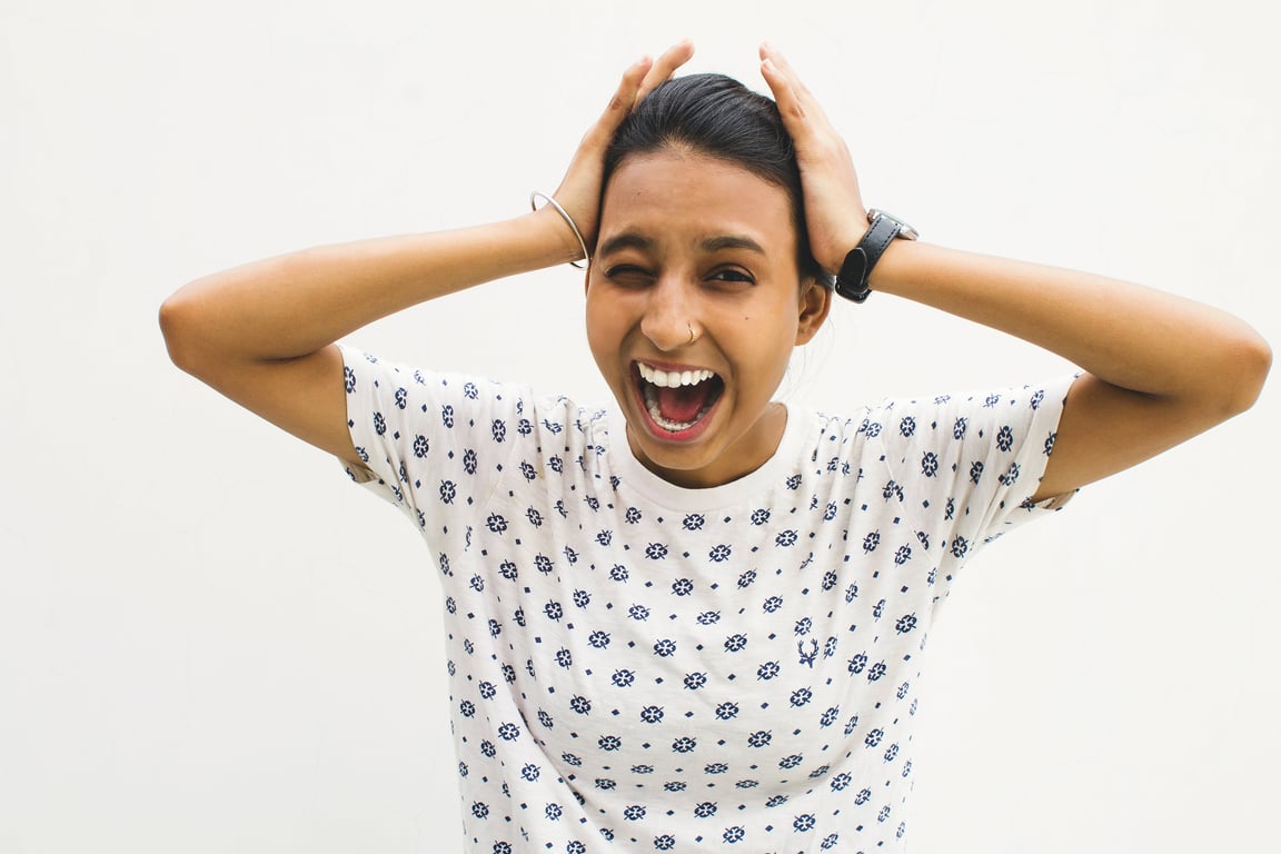 Woman screeming with hands over ears showing signs of high functioning anxiety